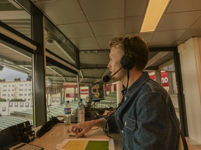 Lloyd commentating from a stadium commentary box