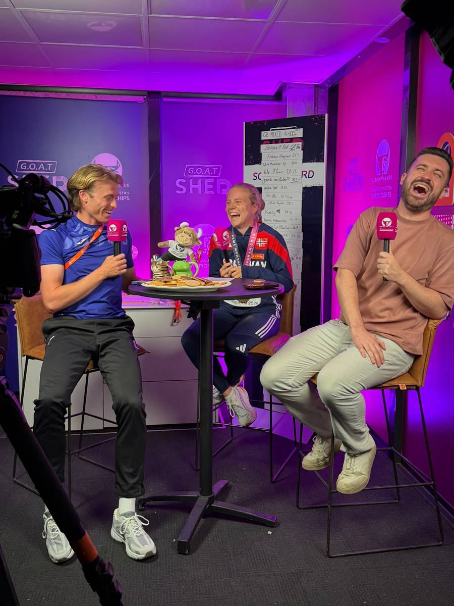 Lloyd and a co-host laughing with a medallist in the GOAT Shed studio