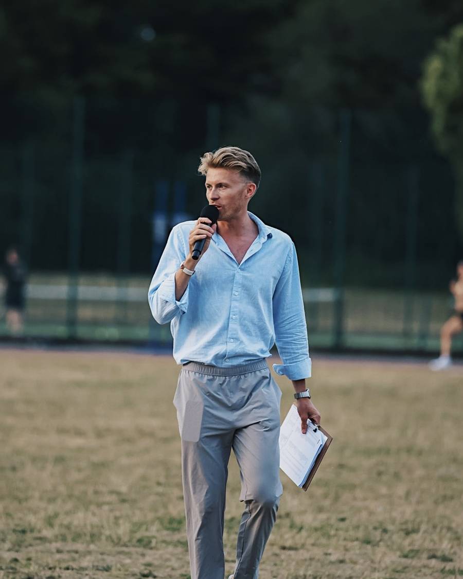 Lloyd walking across an infield with a microphone and clipboard